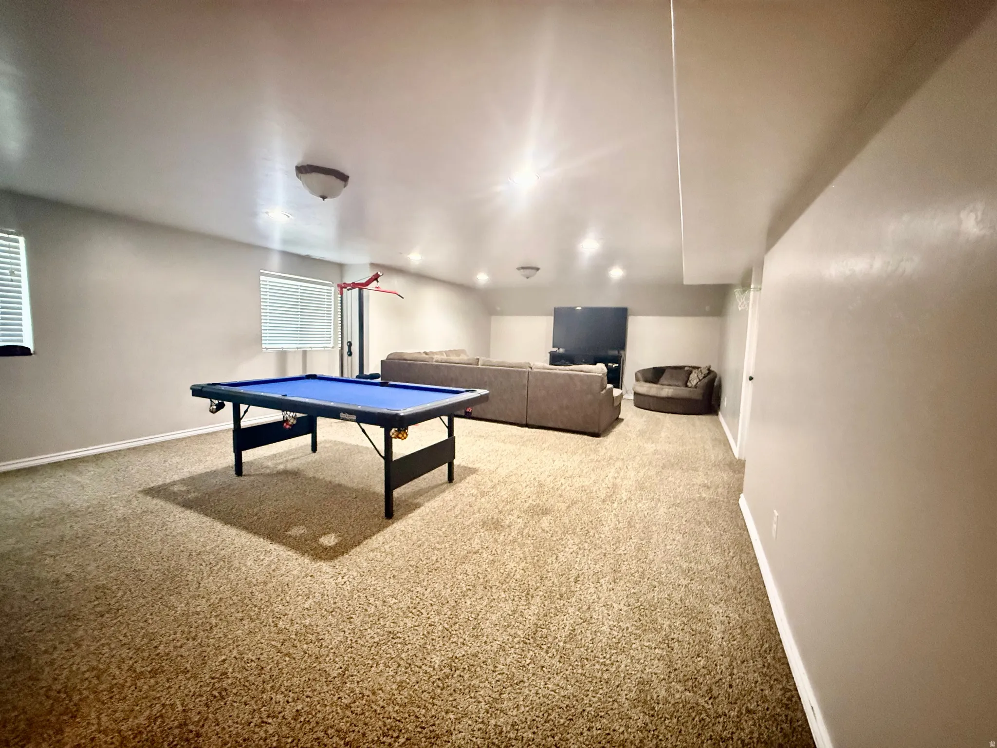 Spacious lower-level room featuring light tan carpeting and neutral wall tones