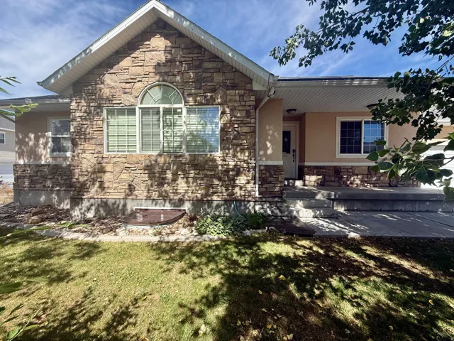 Stone and stucco exterior featuring an arched window, white-framed windows, a covered entry, and a concrete porch with steps