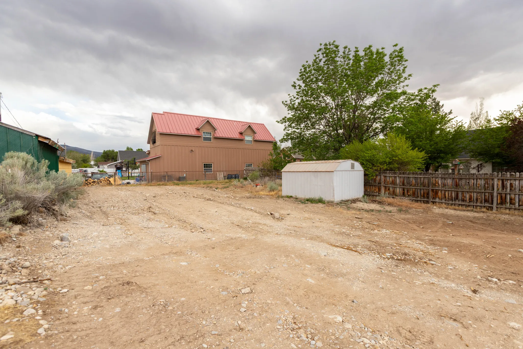 Expansive cleared lot featuring a storage shed and partial wood fencing