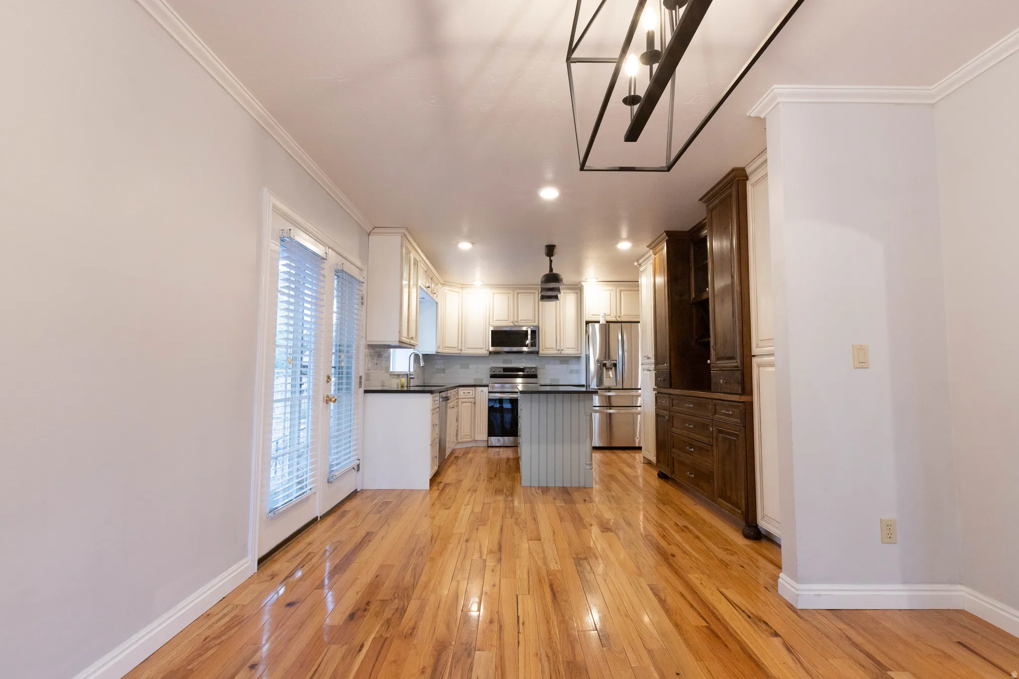 Open-concept kitchen featuring wood-finish flooring, recessed lighting, and a kitchen island with a dark countertop