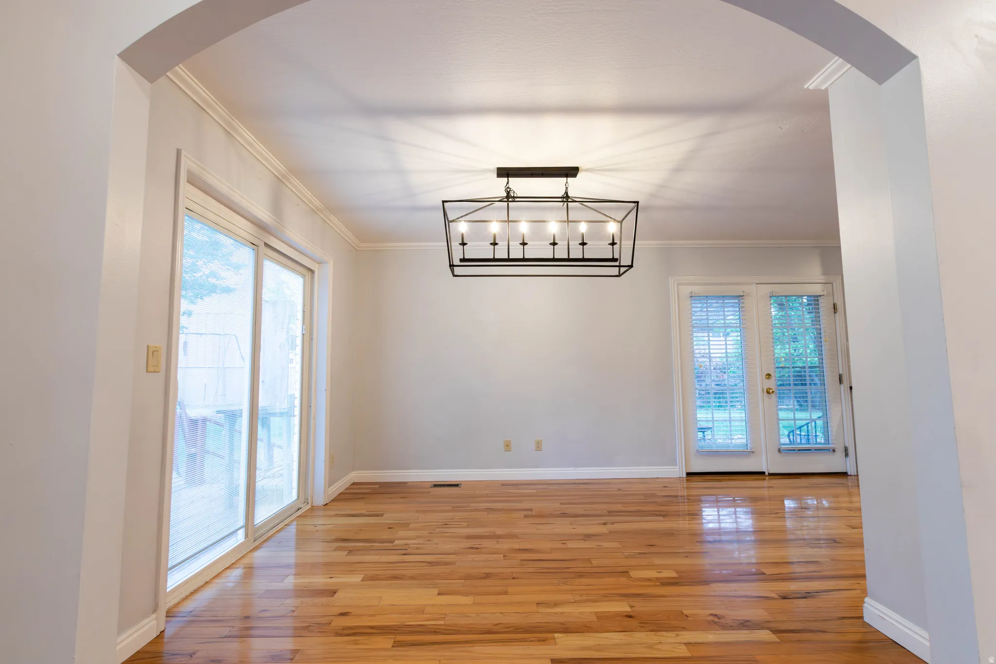 Open concept room with hardwood flooring and crown molding