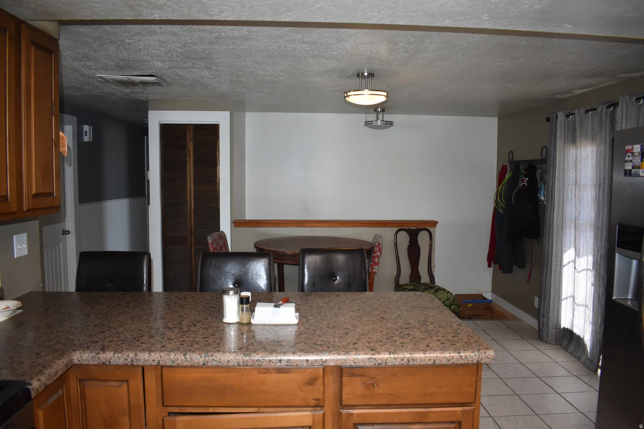 Kitchen and dining area featuring wood-finish cabinetry, a speckled countertop, and tiled flooring