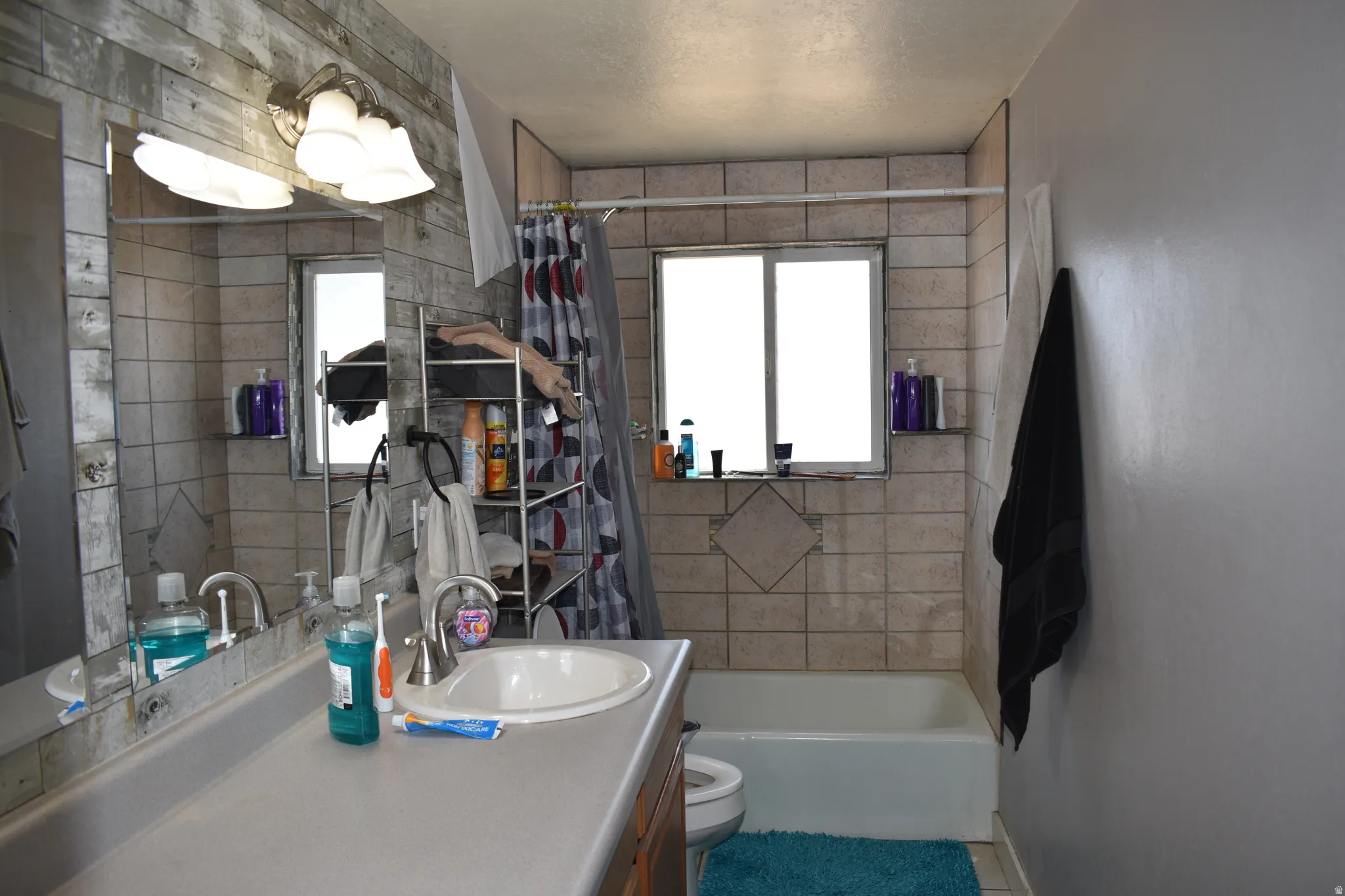Bathroom featuring a vanity with an integrated sink, a rectangular mirror, and a wall-mounted light fixture