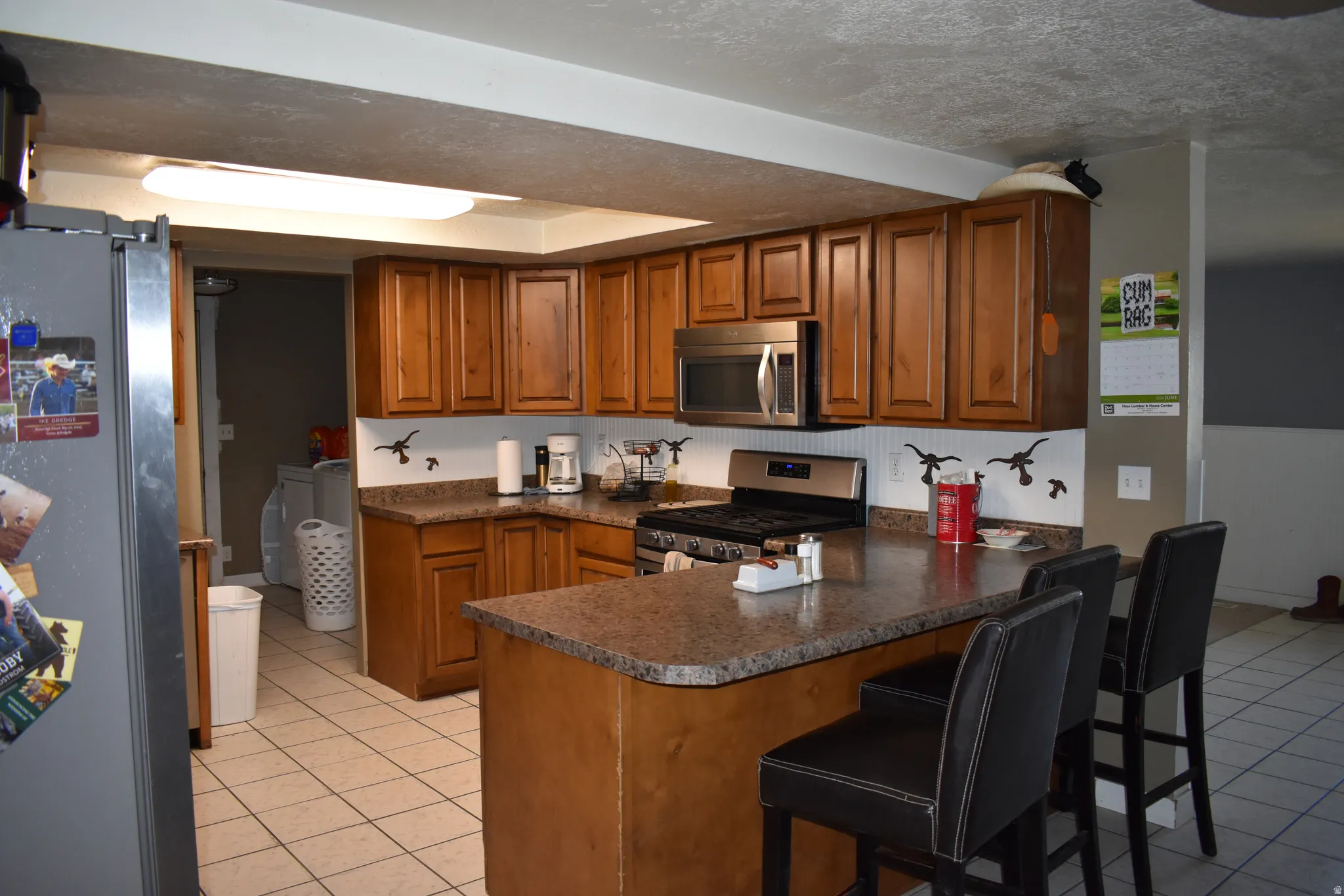 Kitchen featuring wood cabinetry, stainless steel microwave, gas range, and a breakfast bar with seating