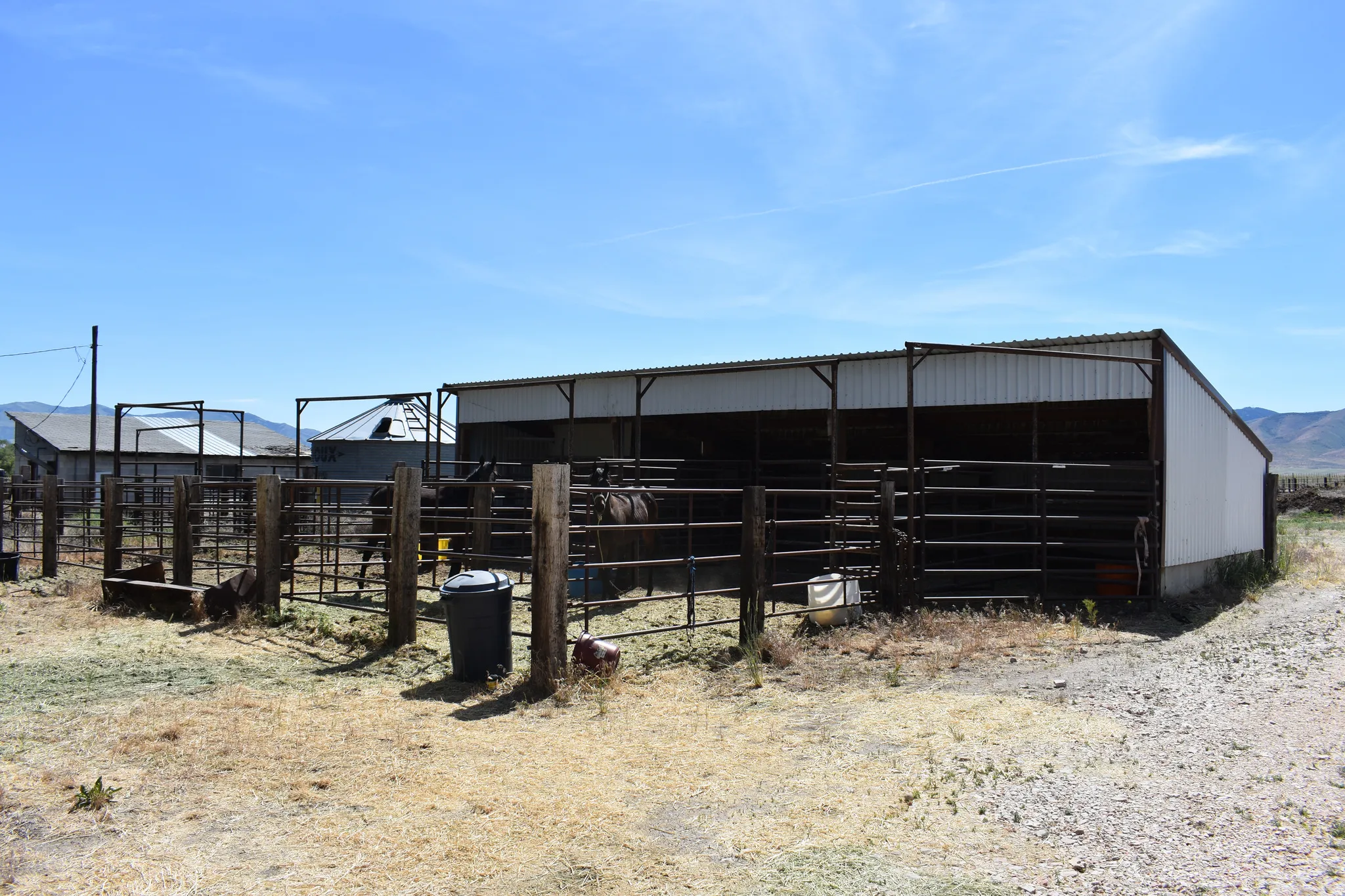Metal-sided barn structure with an open-air design, featuring a corrugated metal roof