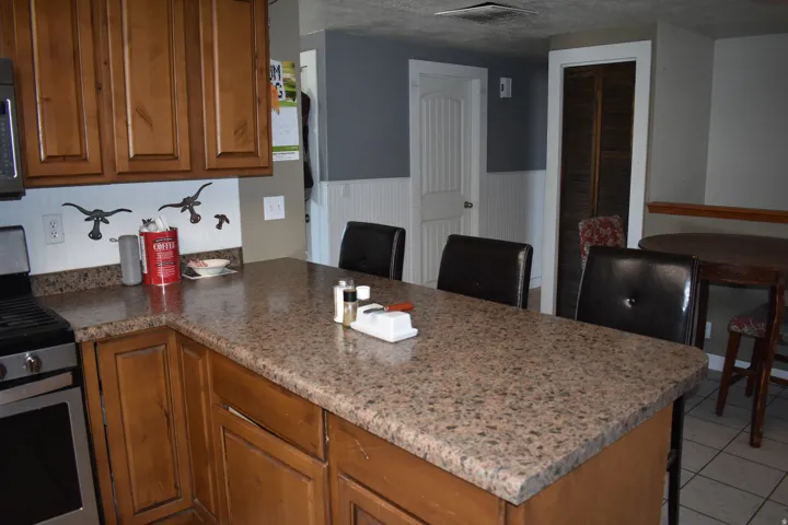 Kitchen featuring a speckled countertop island, wood cabinetry, built-in gas range, and tile flooring