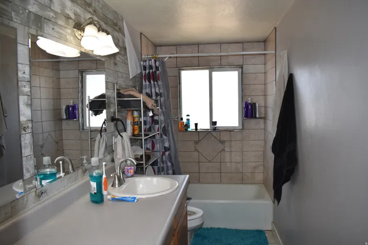 Bathroom featuring a vanity with an integrated sink, a rectangular mirror, and a wall-mounted light fixture