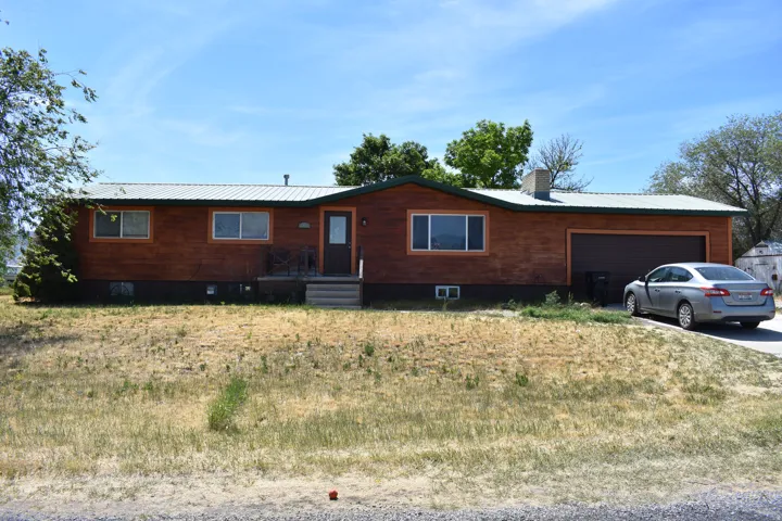 Ranch-style residence featuring wood-paneled siding, a metal roof, and a two-car garage