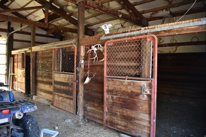 Agricultural structure featuring multiple wood-paneled stalls with metal-framed doors