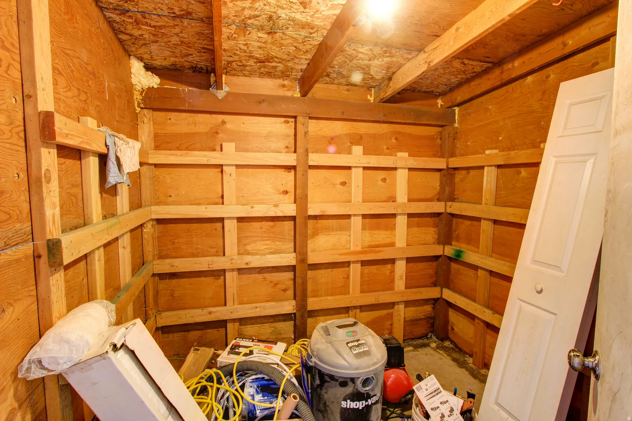 Unfinished interior space featuring plywood paneling and exposed wood framing