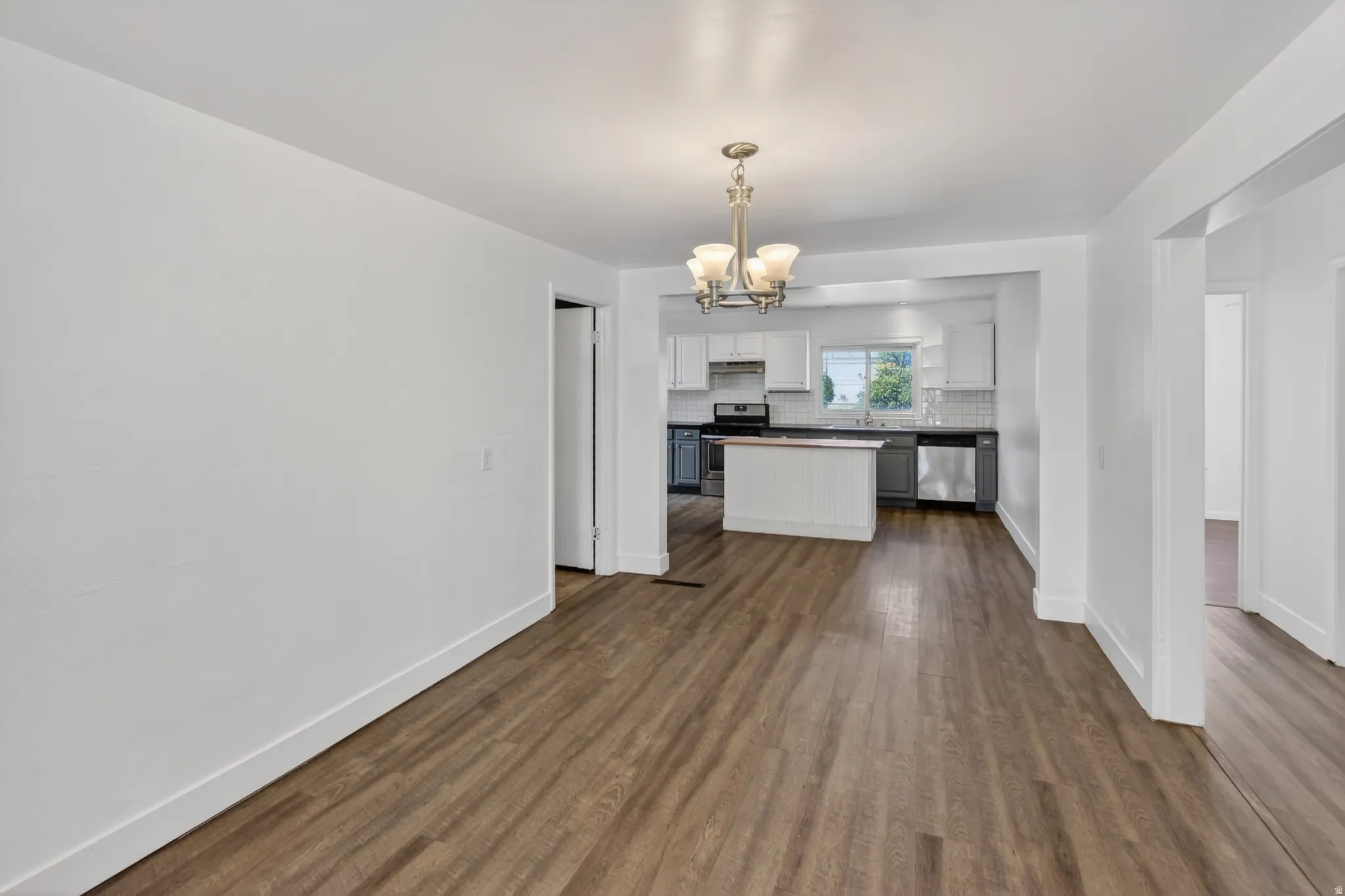 Open-concept living space featuring wood-finish flooring, a contemporary chandelier, and recessed lighting