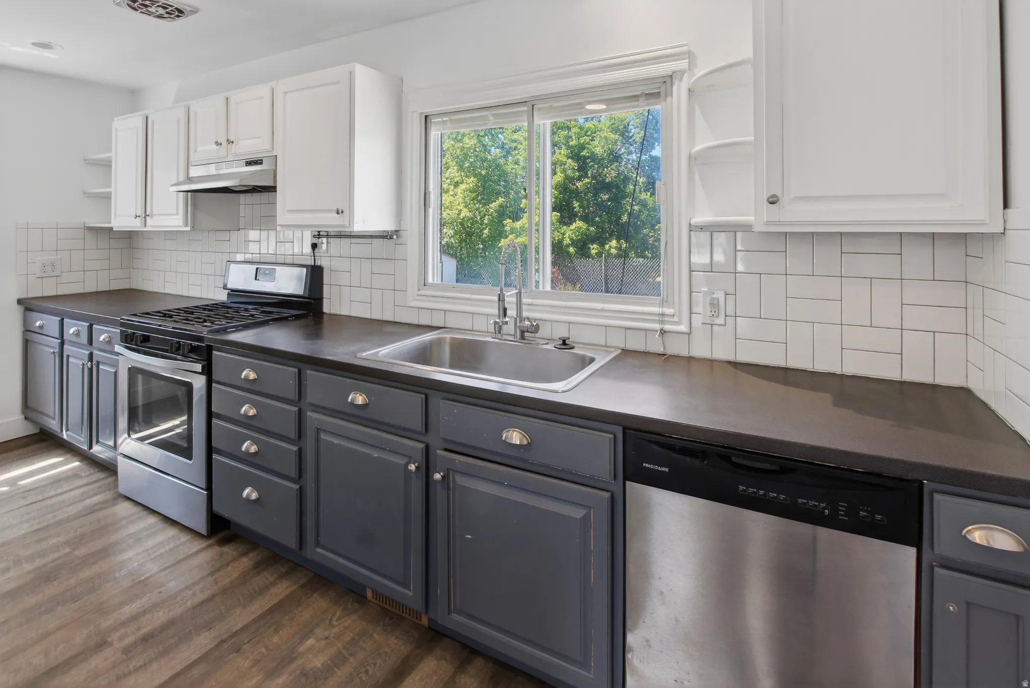 Kitchen featuring two-tone cabinetry with white upper cabinets and gray lower cabinetry, dark countertops, and a white subway tile backsplash