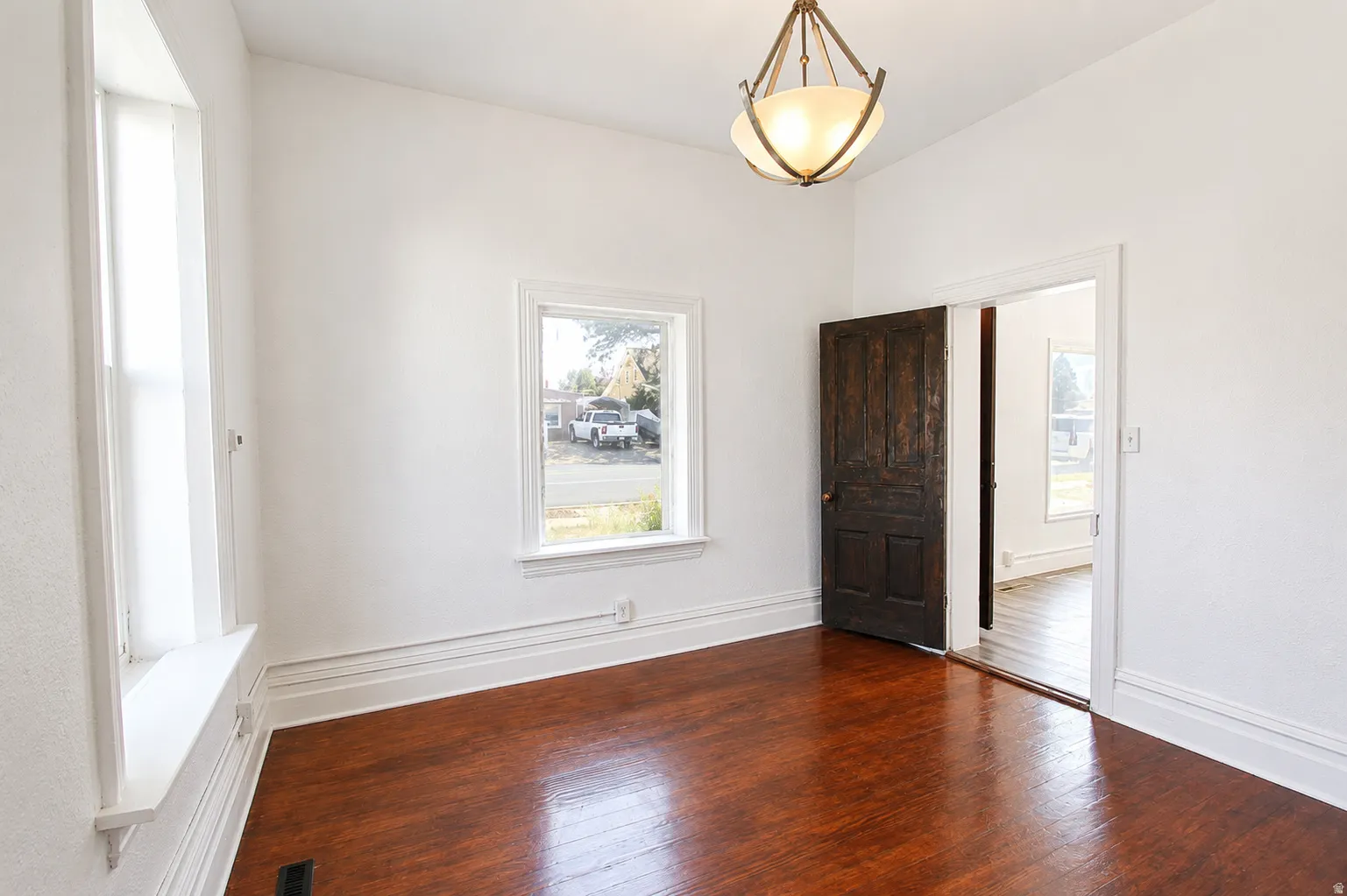 Rich wood-finish flooring with white baseboards