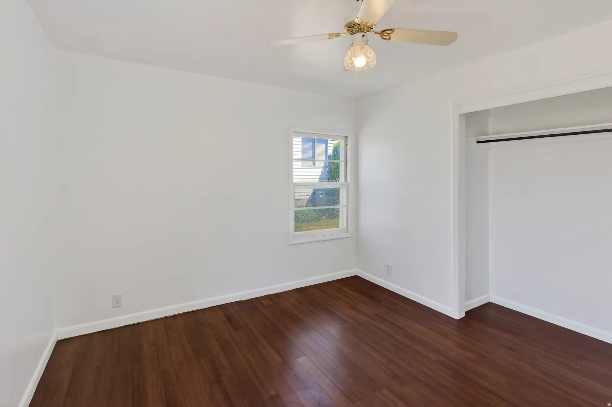 Room featuring wood-finish flooring, white walls, and a window providing natural light