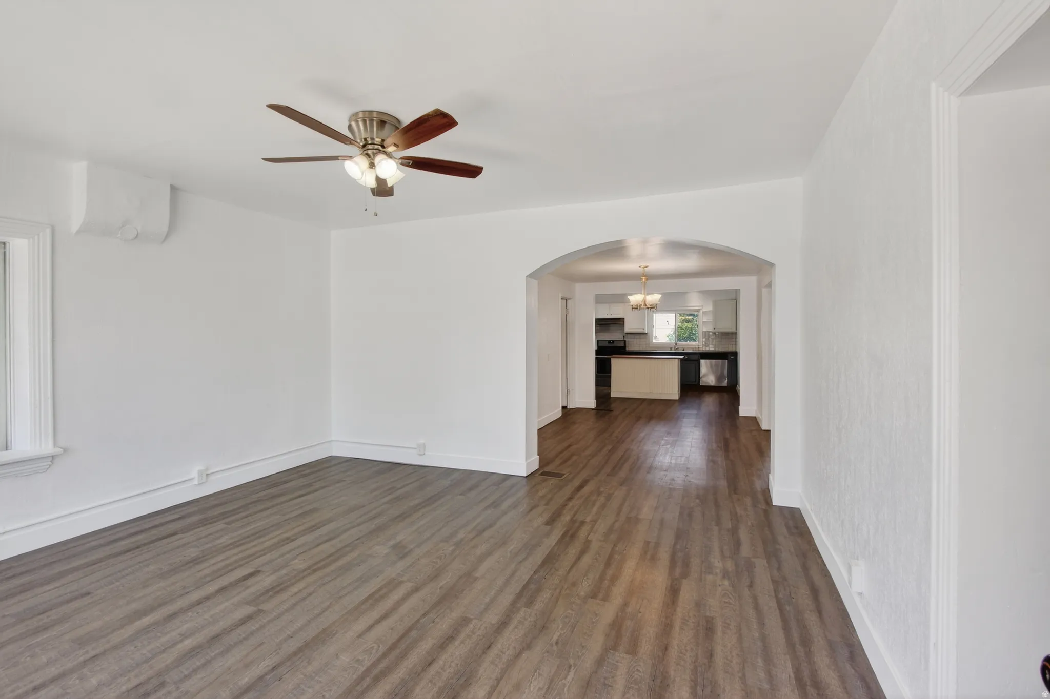Spacious interior featuring wood-finish flooring, an arched doorway, a ceiling fan, and a mini-split air conditioning unit
