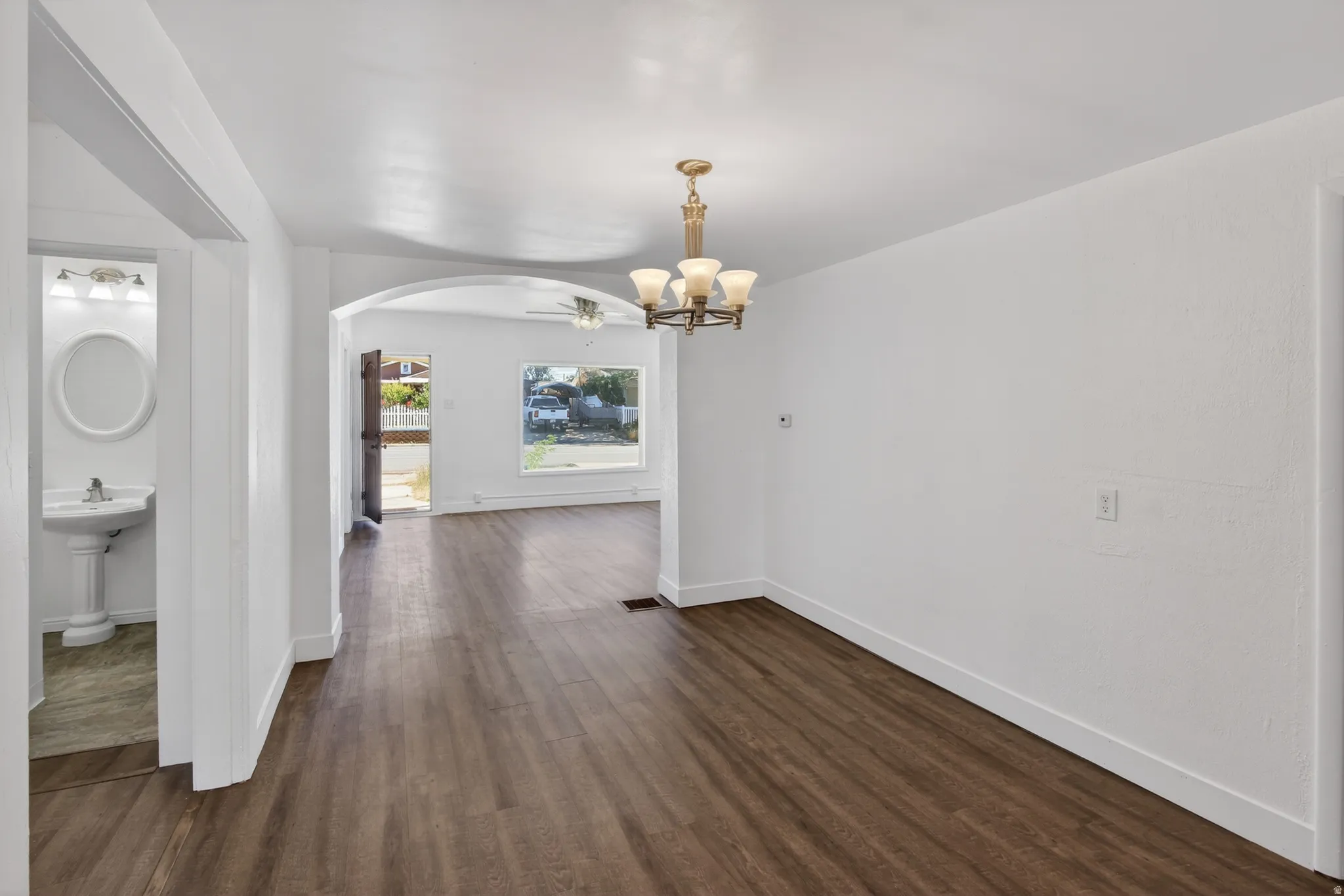 Open concept living area featuring wood-finish flooring, white walls, and a chandelier light fixture