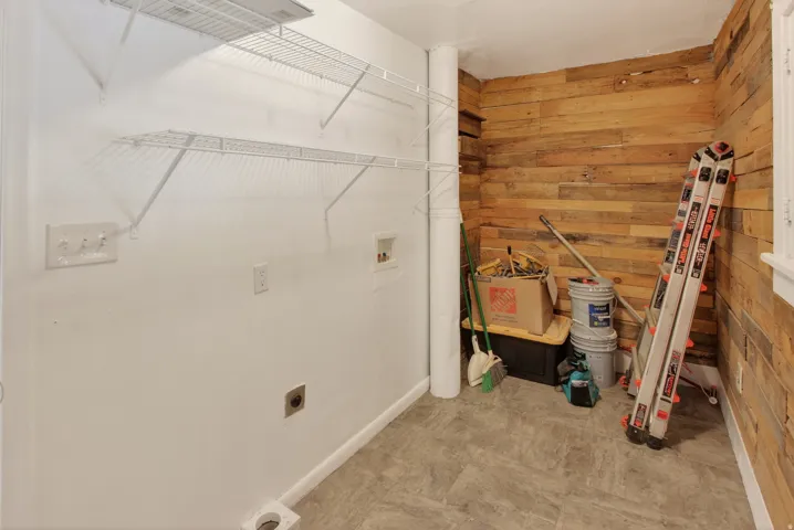 Laundry area featuring wire shelving, wood plank accent wall, and vinyl plank flooring