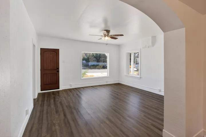Open living area featuring wood-finish flooring, an arched entryway, and multiple windows for natural light