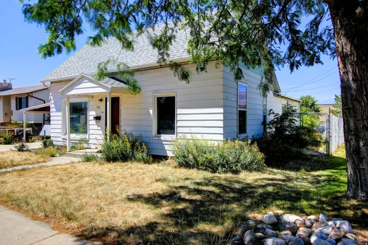 White siding exterior with a pitched shingle roof, featuring a covered front entry and established perimeter landscaping