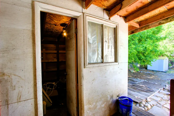 Exterior wall with a window and an open doorway leading to a storage area
