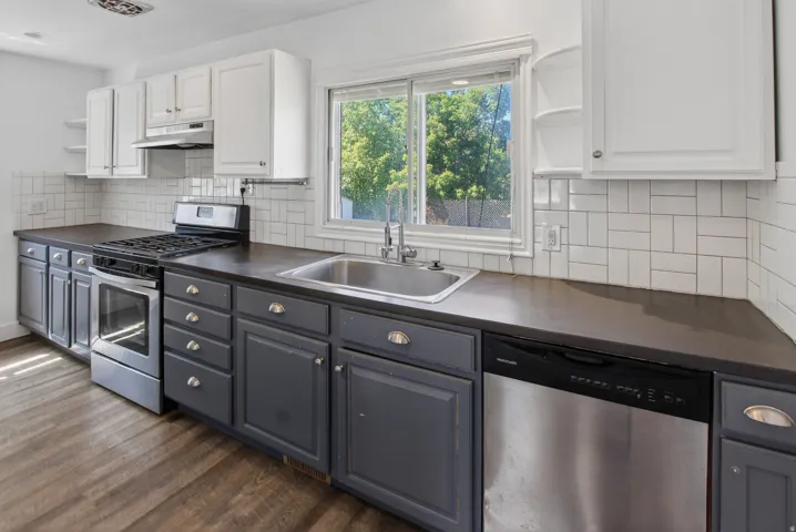 Kitchen featuring two-tone cabinetry with white upper cabinets and gray lower cabinetry, dark countertops, and a white subway tile backsplash