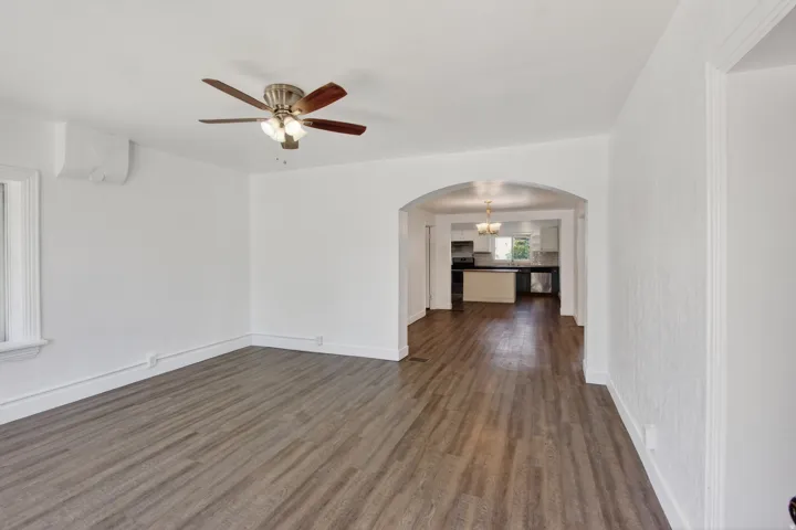 Spacious interior featuring wood-finish flooring, an arched doorway, a ceiling fan, and a mini-split air conditioning unit