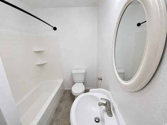 Bathroom featuring a white bathtub with tile surround, a built-in corner shelf, and a black shower rod