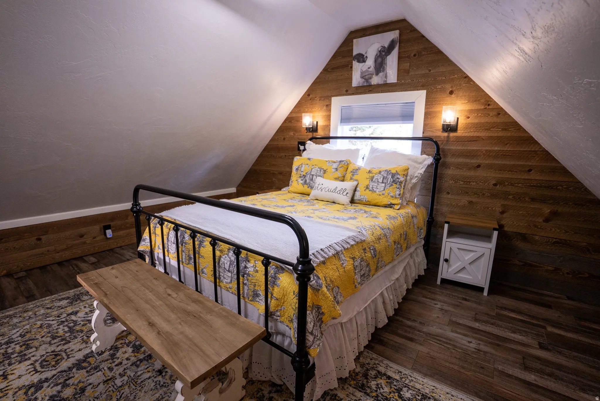 Bedroom featuring wood-finish flooring, exposed wood plank wall, sloped ceilings, and built-in wall sconces