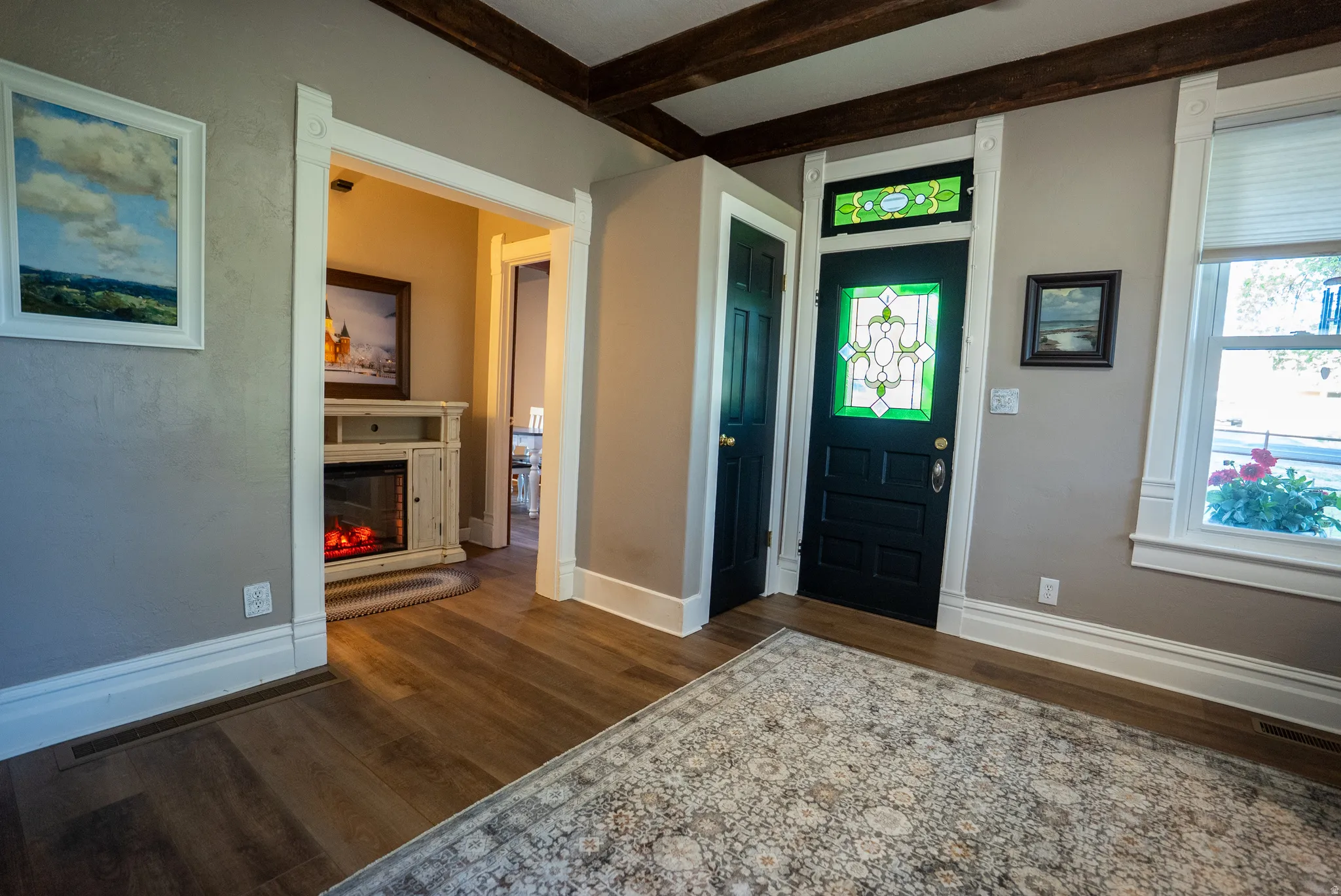 Hardwood-finish flooring extending from the entryway, featuring a prominent dark-paneled door with decorative stained glass
