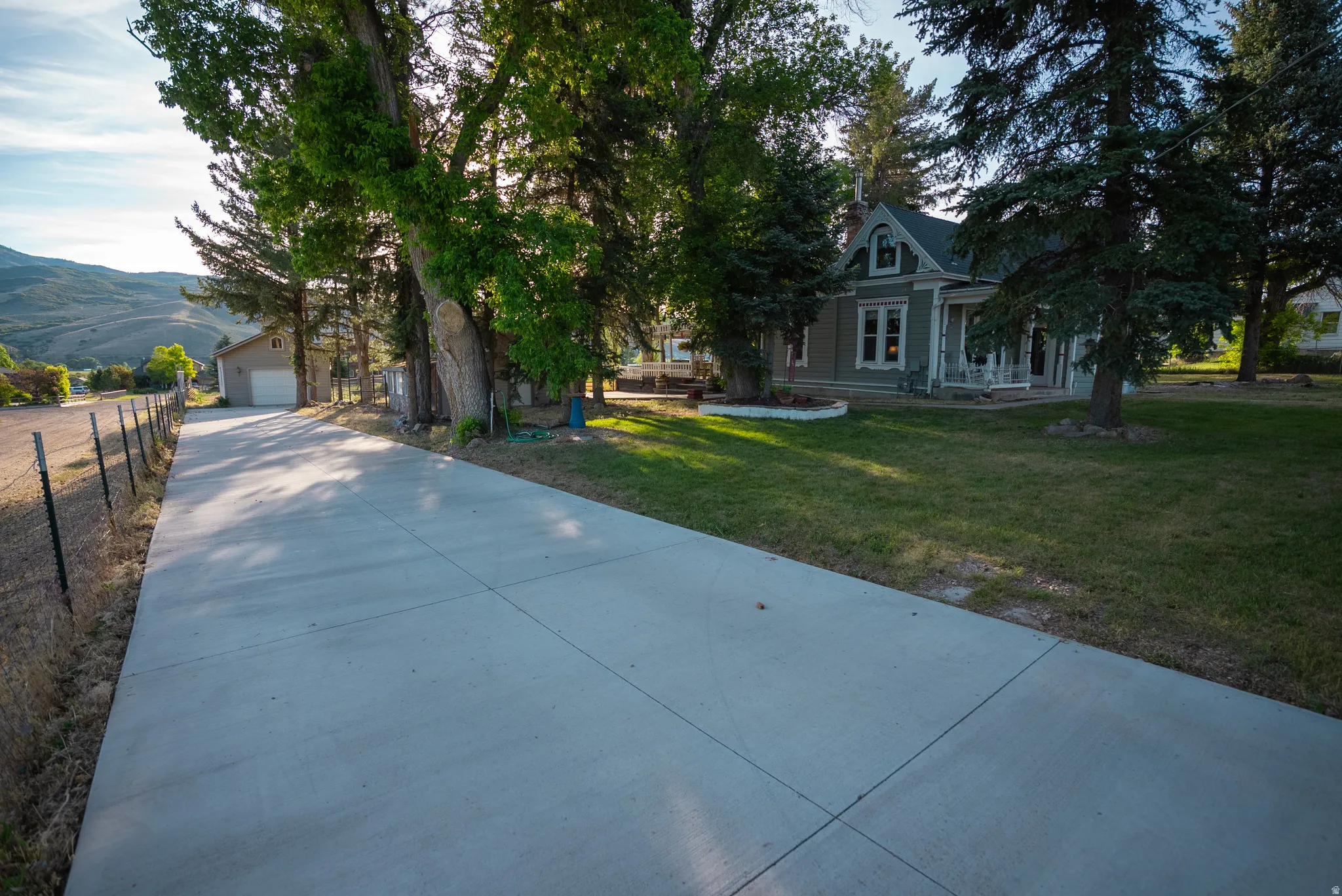 Long concrete driveway providing access to a detached garage and a traditional-style residence with a covered porch and dormer window