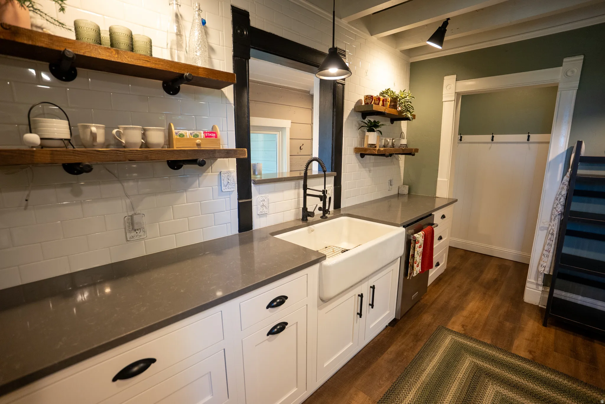 Kitchenette featuring a farmhouse sink, dark stone-finish countertops, subway tile backsplash, and wood-finish flooring