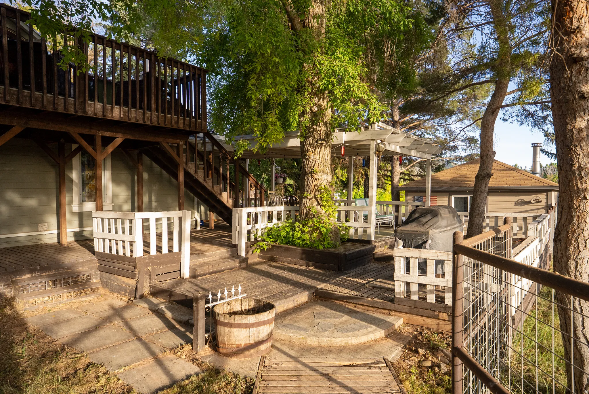 Multi-level outdoor deck featuring a pergola, wood railings, built-in planters, and an exterior staircase