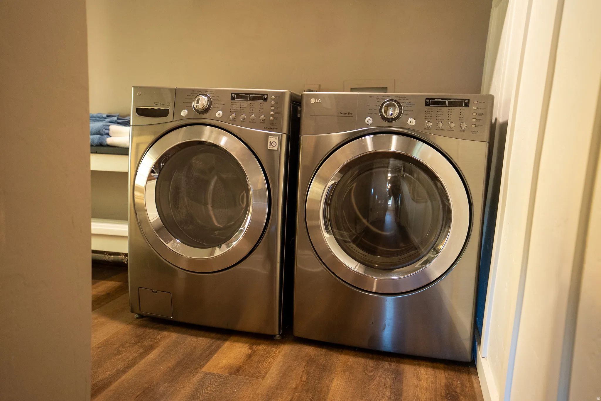 Dedicated laundry area featuring dual front-loading appliances, wood-finish flooring, and neutral wall tones