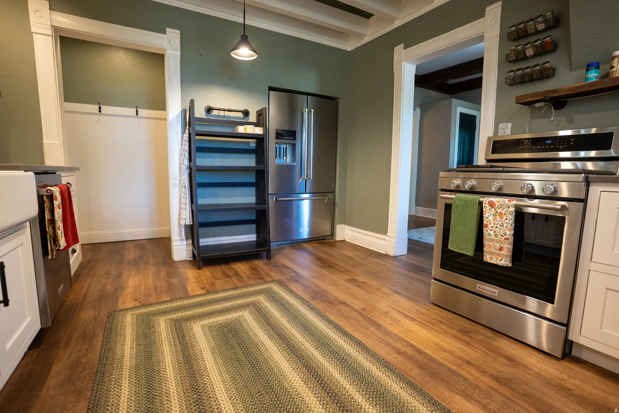 Gourmet kitchen featuring stainless steel appliances, wood-finish flooring, white cabinetry, and a farmhouse sink