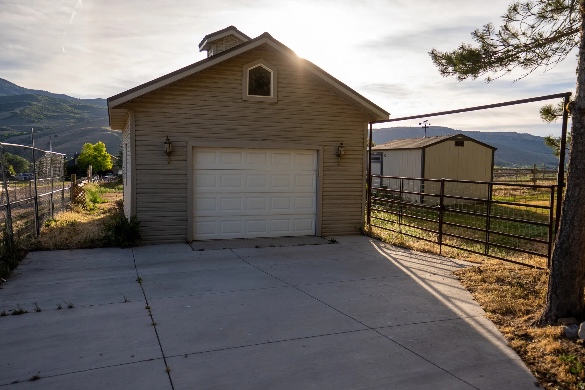 Detached garage with horizontal siding, a single panel garage door, and a cupola