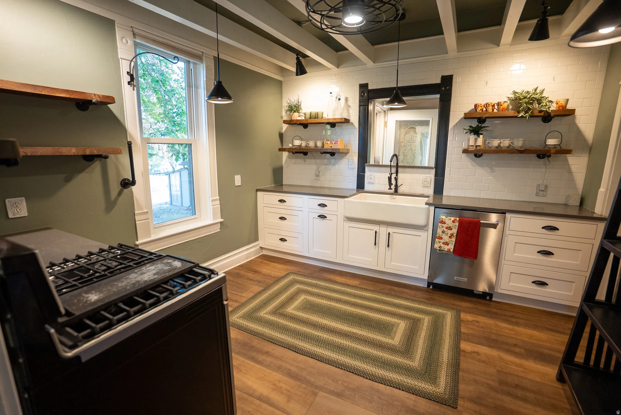 Modern kitchen featuring a farmhouse-style sink, white cabinetry, dark countertops, and stainless steel appliances