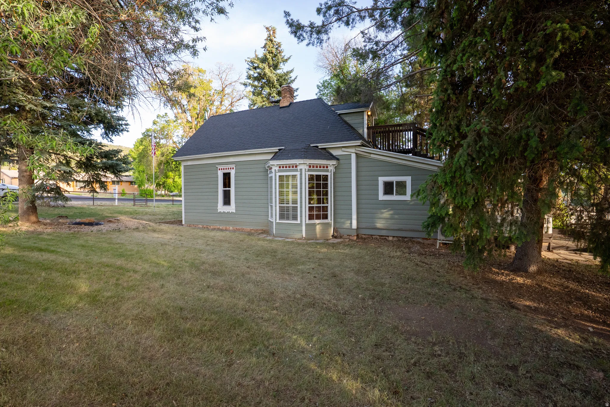 Exterior showcasing a bay window, a second-story deck, and a dark shingle roof