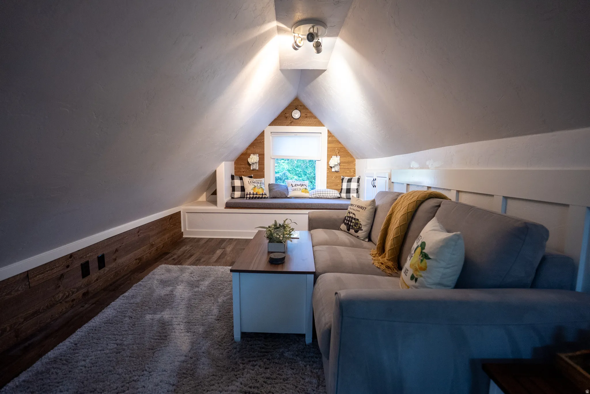 Attic space featuring wood-finish flooring, a built-in window seat, and sloped ceilings