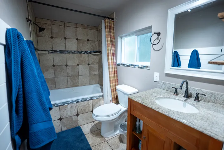 Bathroom featuring a wood-finish vanity with a granite-style countertop, undermount sink, and oil-rubbed bronze fixtures