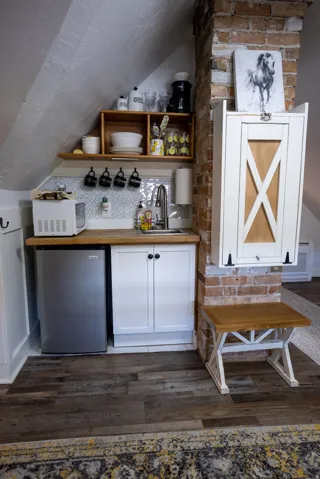 Compact kitchen area featuring wood-finish flooring, white cabinetry, and a stainless steel undercounter refrigerator