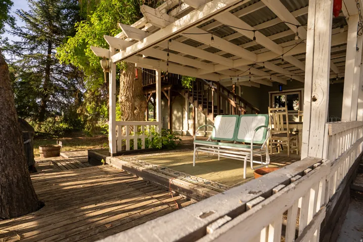 Expansive outdoor decking featuring a covered patio with string lighting, painted wooden railing, and a visible exterior staircase