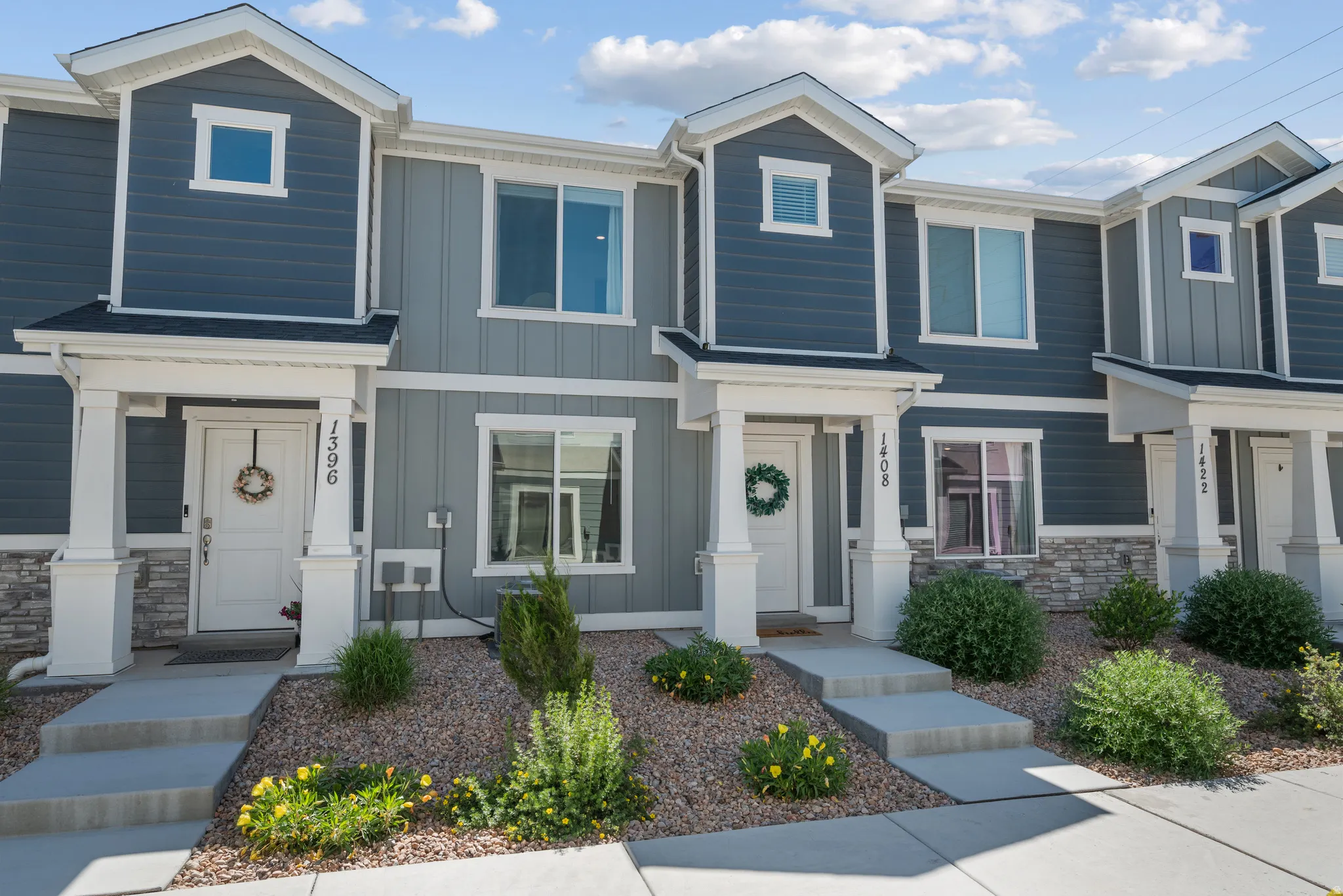 Modern townhome exterior featuring multi-toned siding, white trim, and stone veneer accents