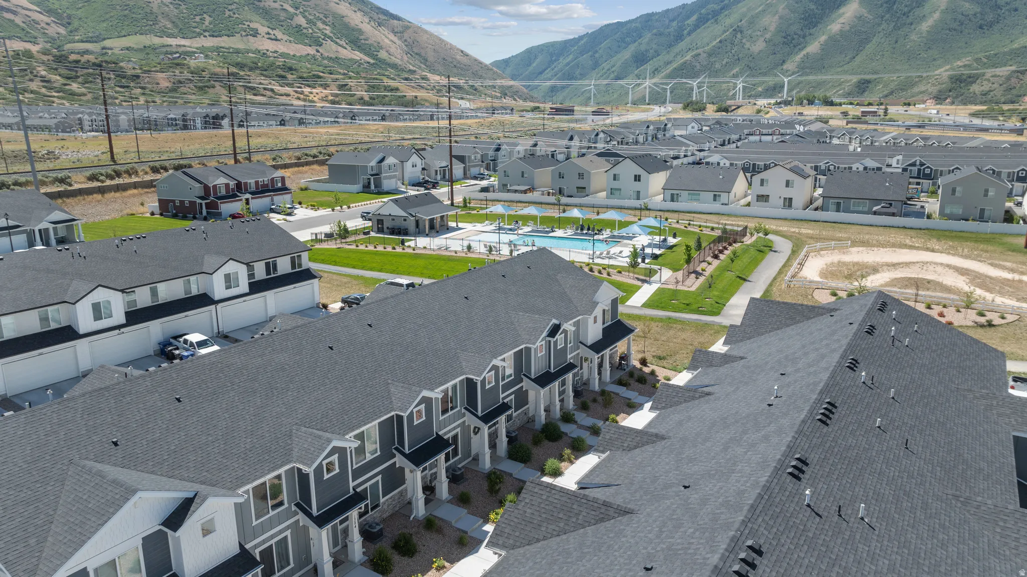 Aerial view showcasing a community with multiple residential buildings, a swimming pool area, and mountain scenery