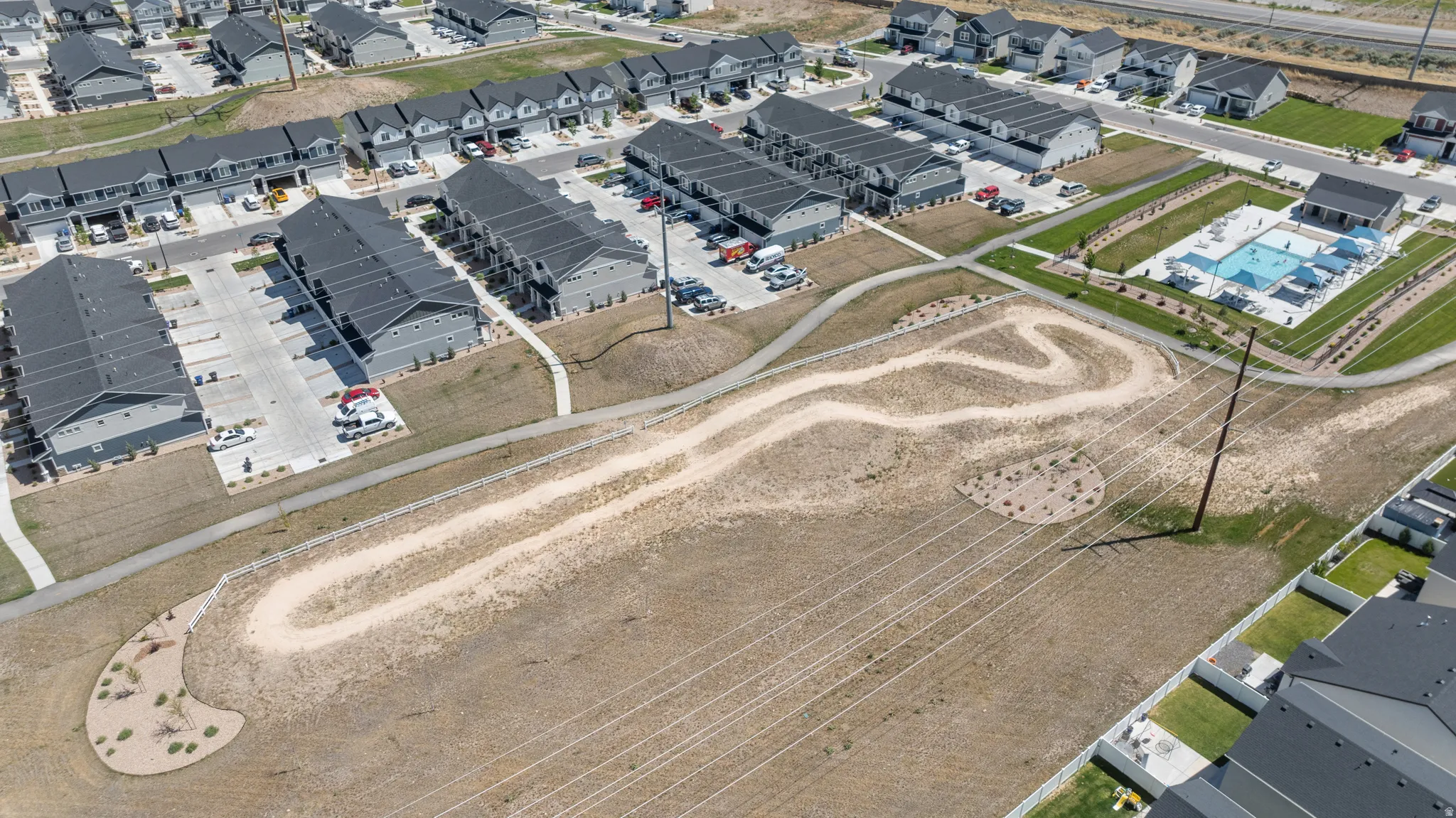 Community featuring multi-unit residential buildings, a swimming pool, and a winding dirt path