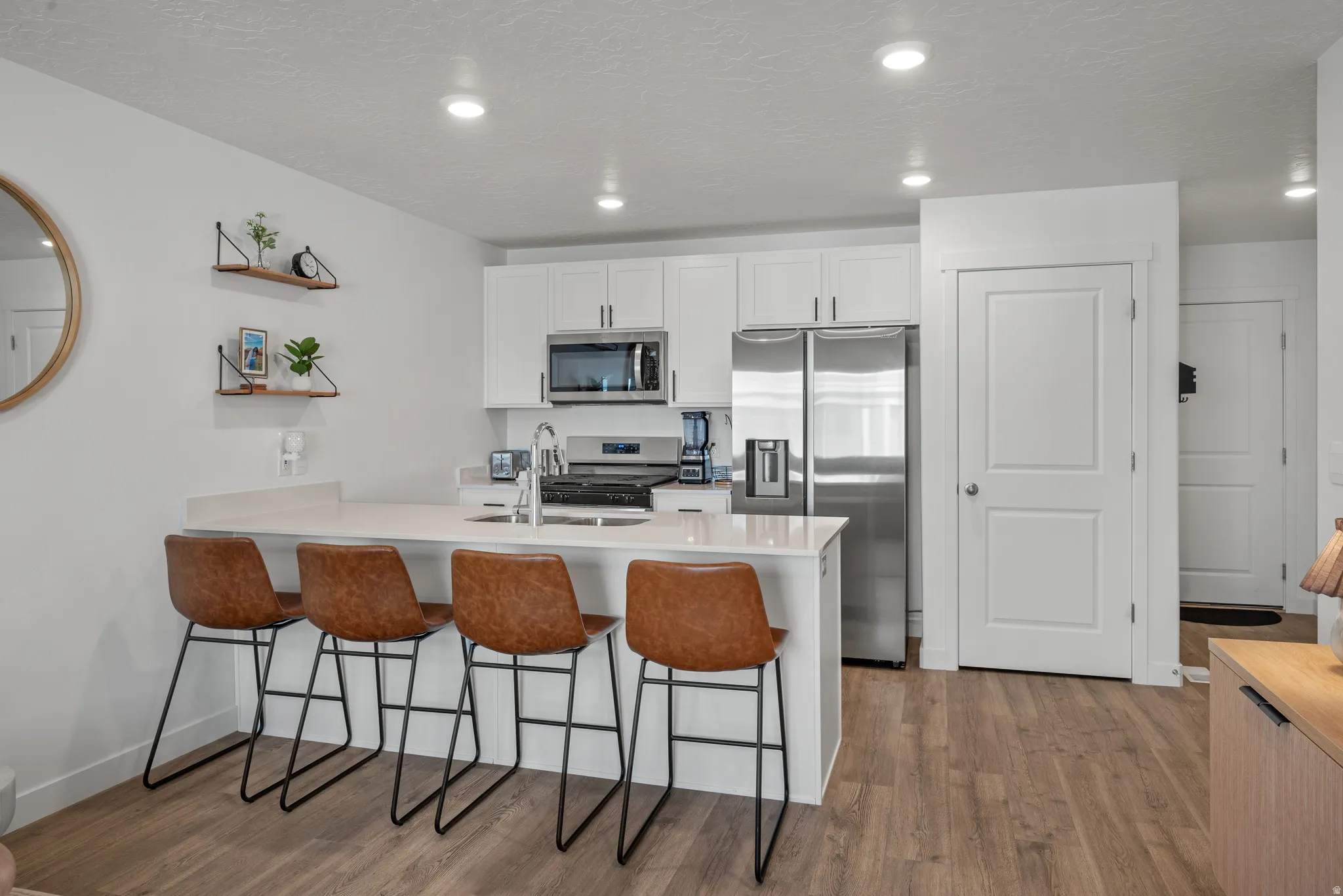 Modern kitchen featuring white cabinetry, stainless steel appliances, recessed lighting, and wood-finish flooring