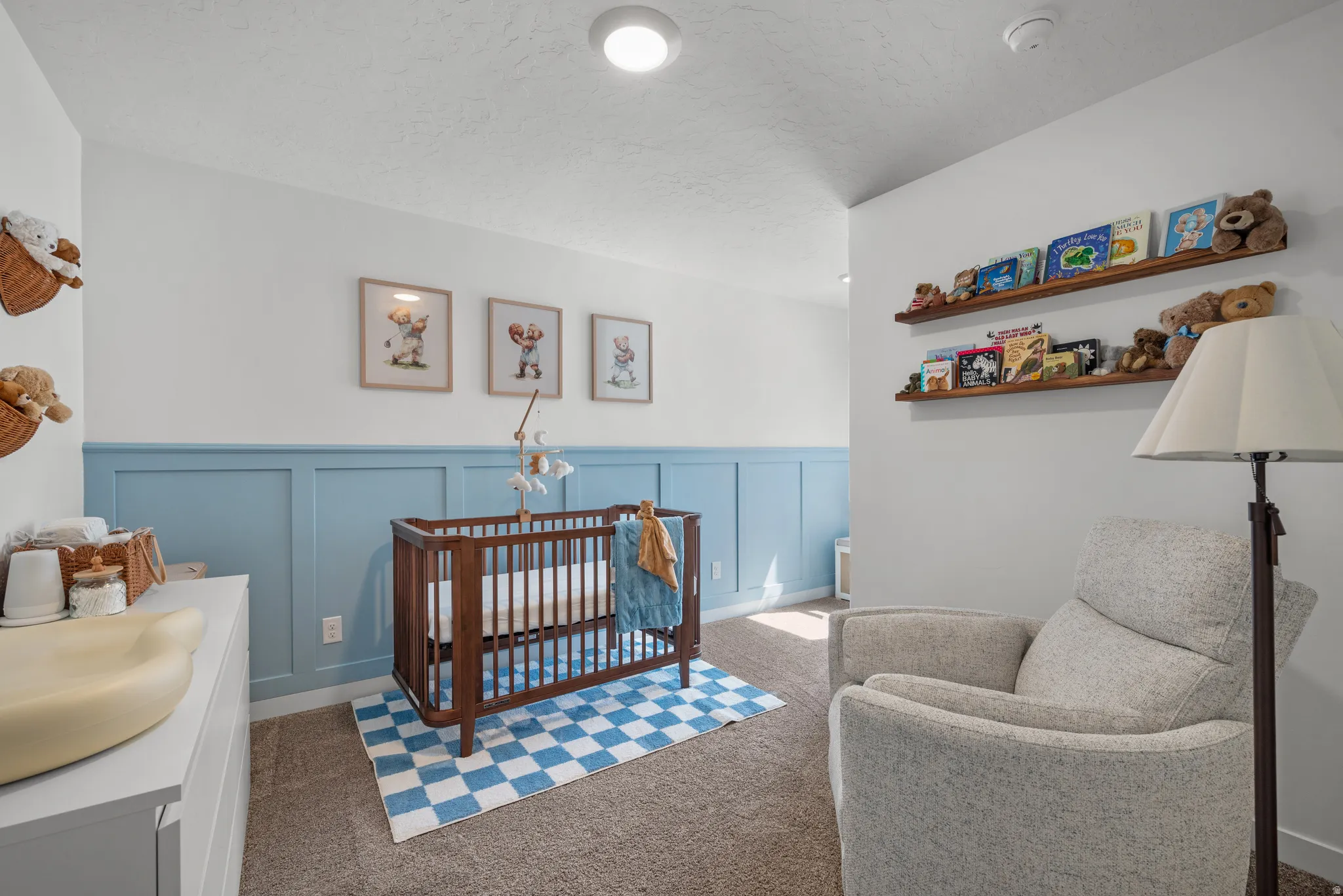 Room featuring two-tone walls with lower wainscoting paneling, upper wall shelving, and carpeting