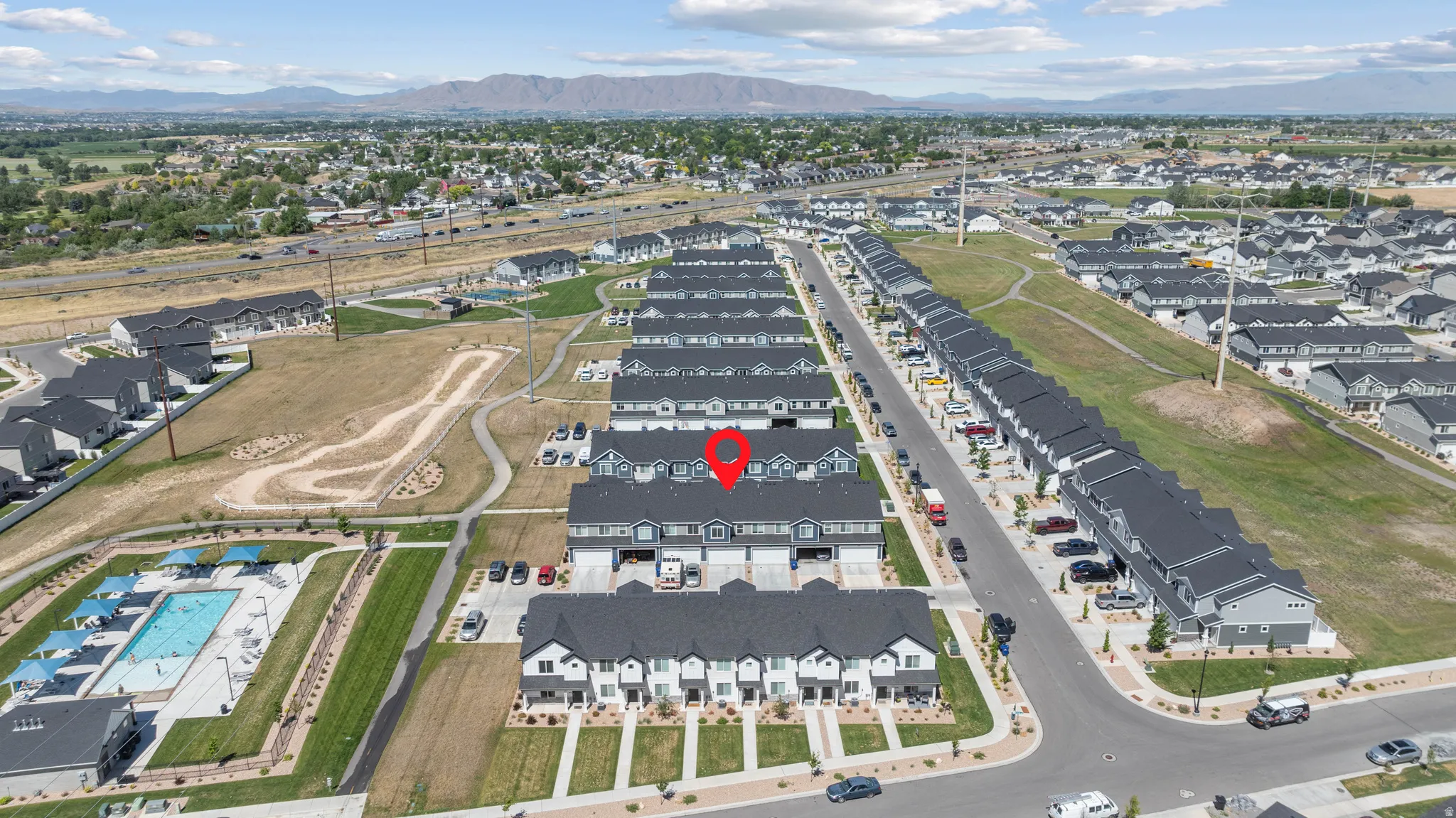 Townhome community featuring a large outdoor swimming pool, paved walking paths, and mountain backdrops