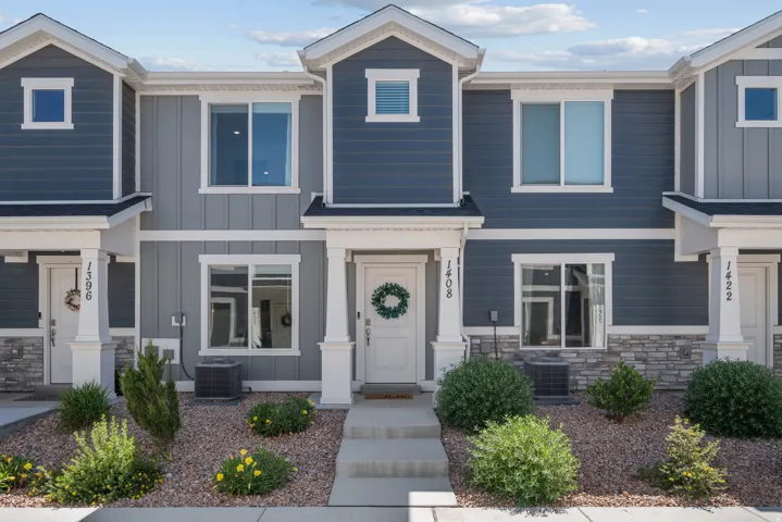Contemporary townhome exterior featuring dual-tone siding, white trim accents, prominent window design, a welcoming entryway, and low-maintenance landscaping