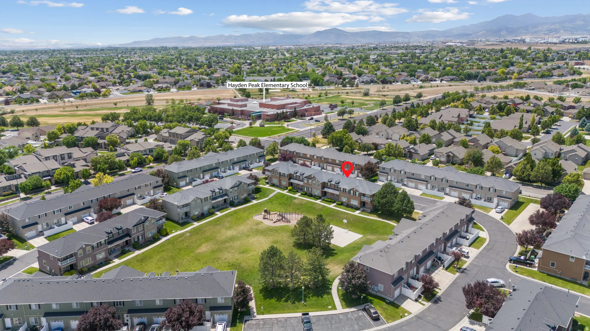 Aerial perspective showcasing a residential community with townhomes and detached houses, featuring green spaces and mature landscaping