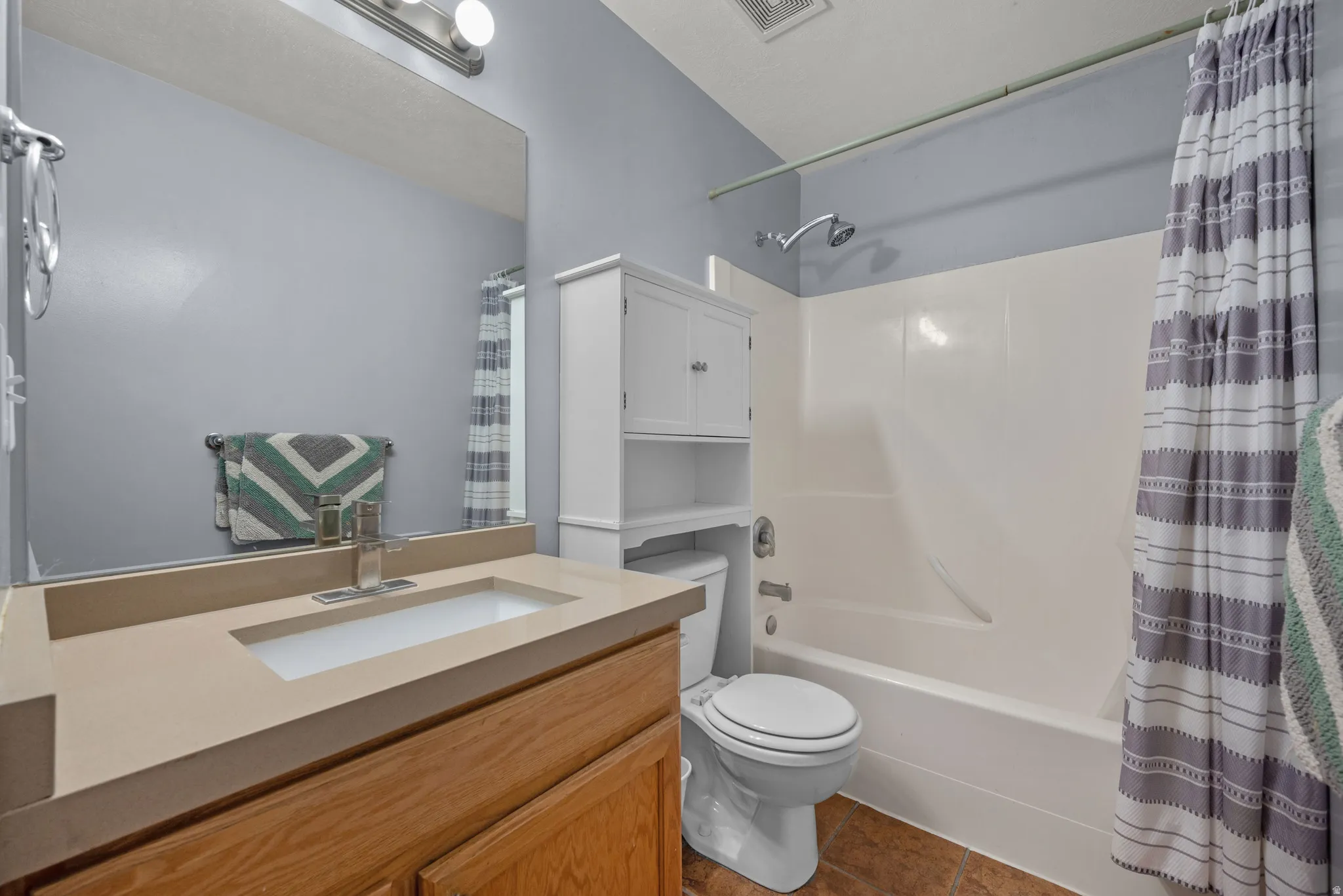Bathroom featuring a wood-finish vanity with an integrated rectangular sink and light-toned countertop